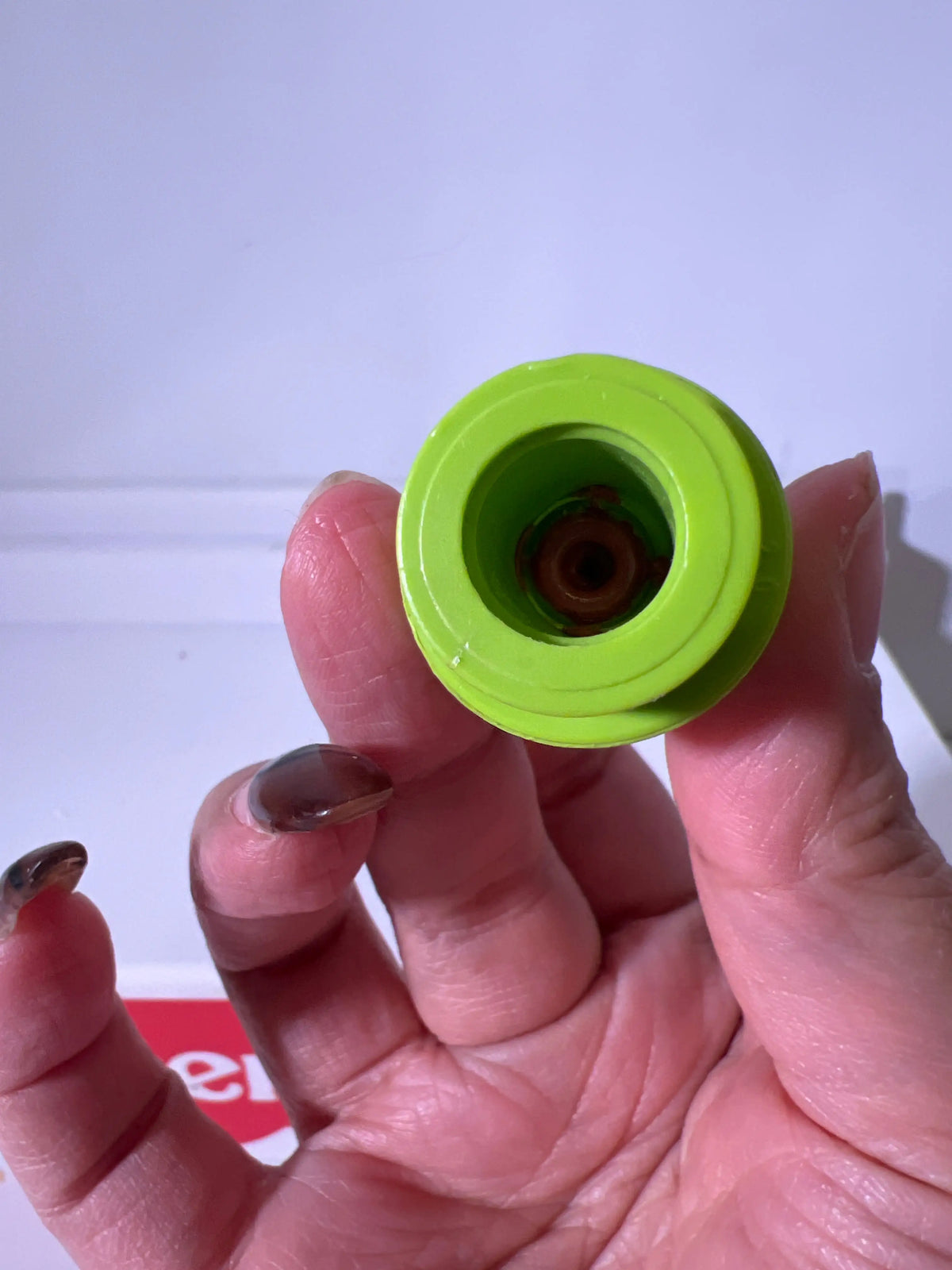Lime green girl figure base, underside close-up held in hand