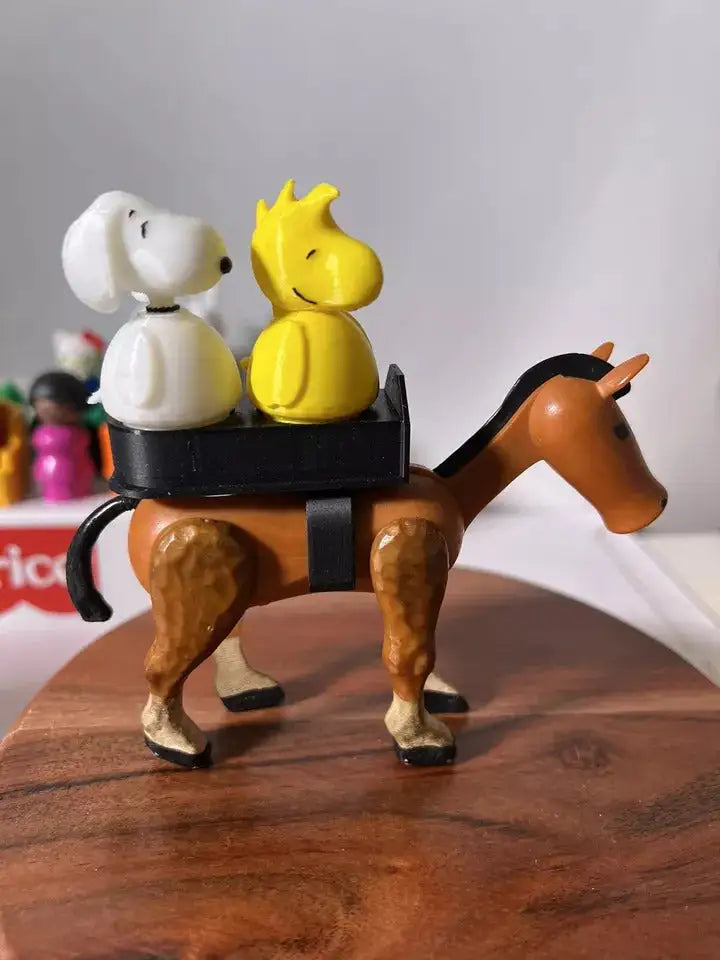 Brown toy horse with black saddle and two figure riders on round wooden base