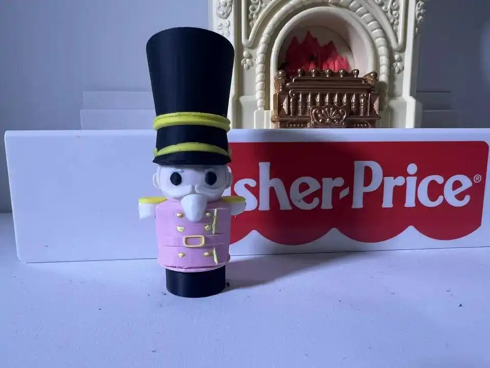 Small nutcracker figurine in black top hat and purple uniform with green trim