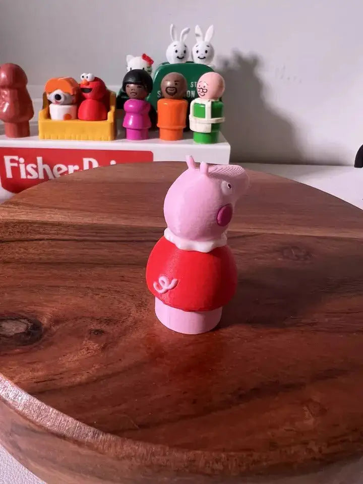 Pink pig figurine facing right, wearing red top with white feet