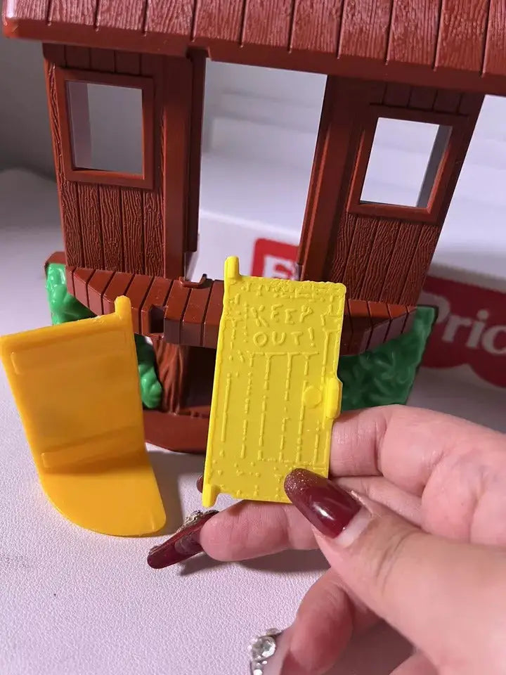 Close-up of yellow toy door panel with raised lettering, held in hand