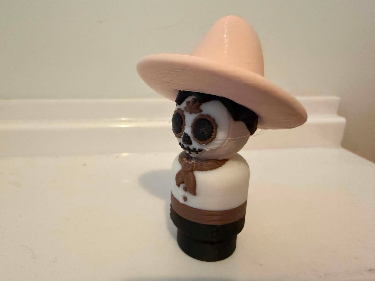 Skeleton man figurine side view wearing beige sombrero and white outfit