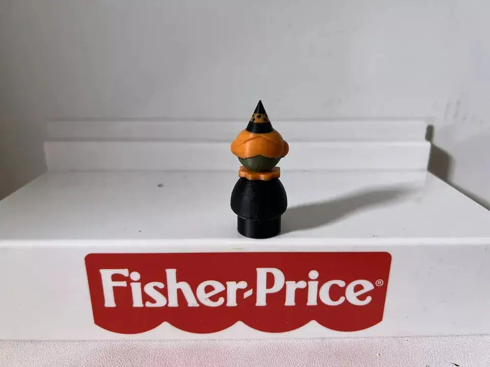 Halloween witch figurine, back angle: black hat and dress with green face and orange collar.