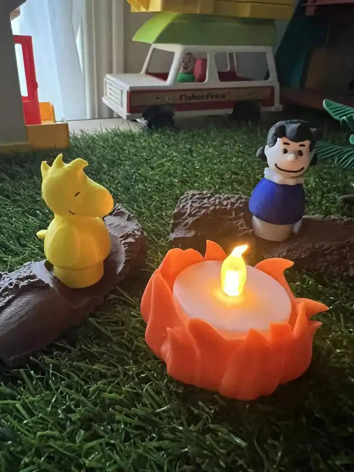 Toy campfire accessory with orange flame on brown logs and character figurines