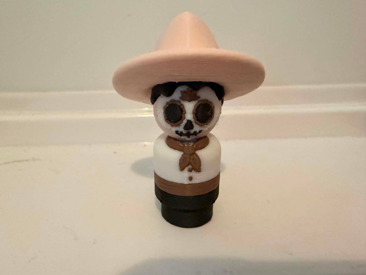 Skeleton man figurine front view with beige hat, white shirt, brown bow