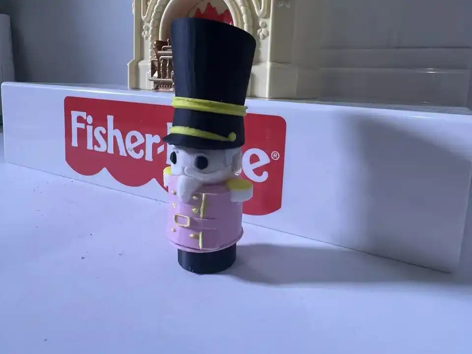 Fisher-Price nutcracker figurine with black top hat and purple uniform, yellow trim
