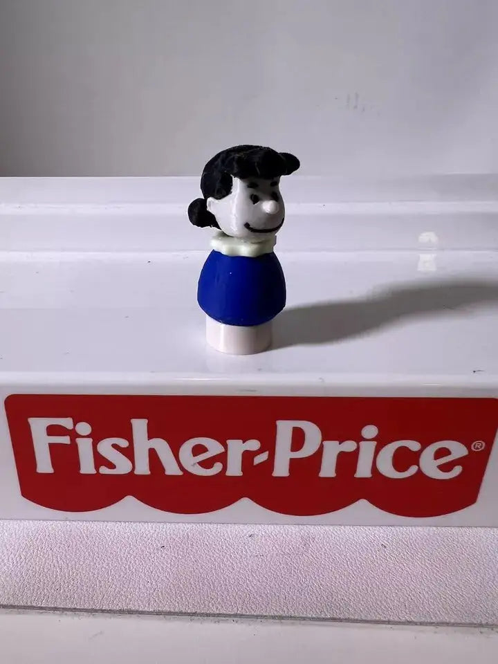 Peanuts Lucy Brown figurine facing away, black hair and blue dress on white base