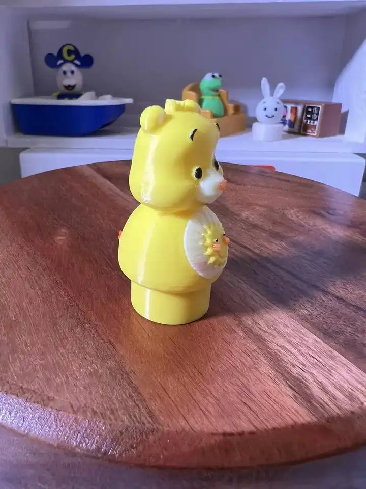 Yellow bear figurine holding a sun badge in one paw, side view