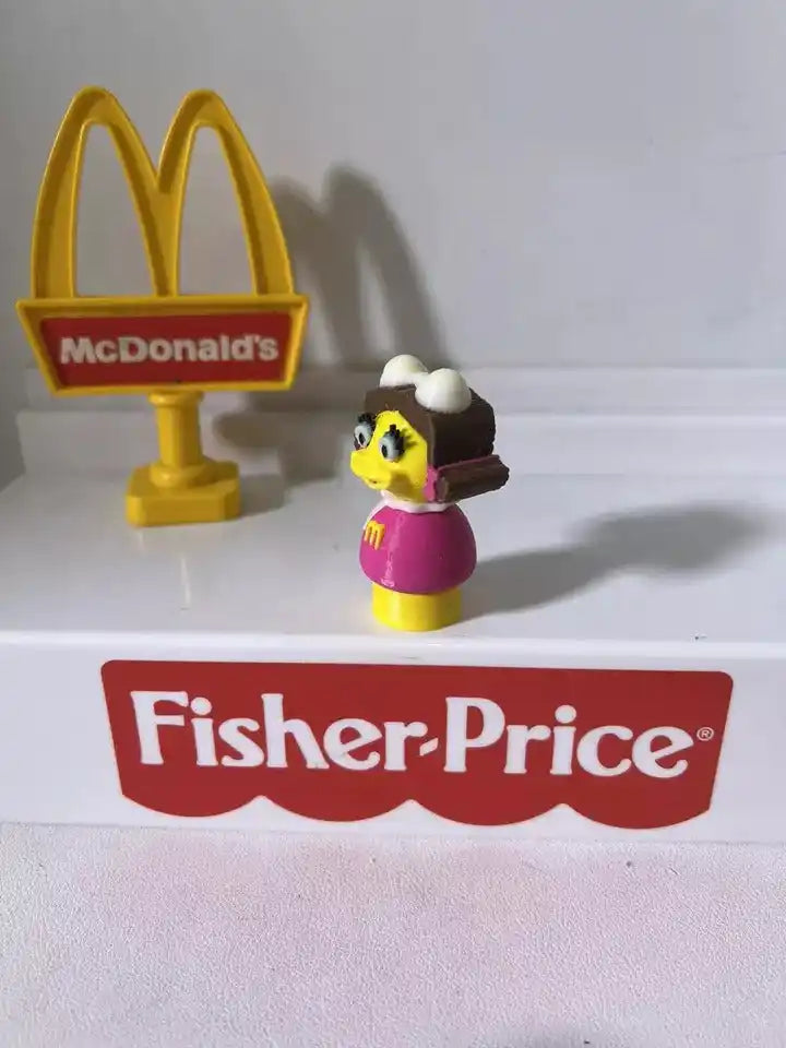 McDonald's Birdie toy figurine, yellow head, black hair, pink dress, on small base