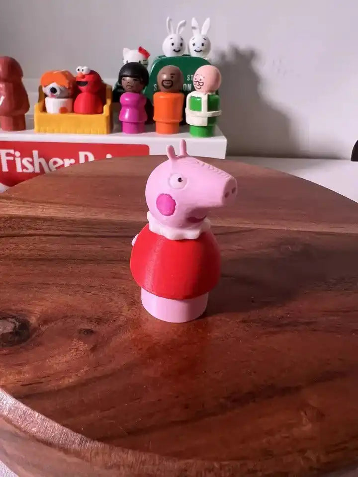 Pink pig figurine facing left, wearing red top and white feet
