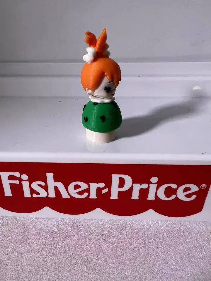 Pebbles Flintstones toy figure with orange hair and green dress, angled view