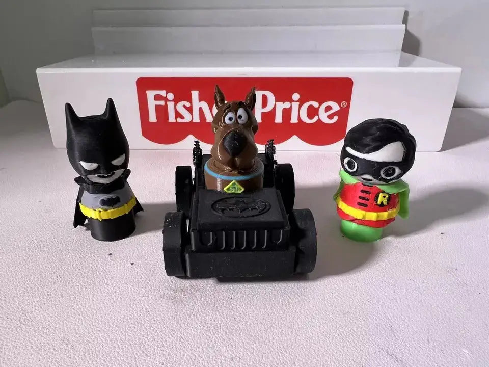 Robin character plush figure with black mask and red-yellow tunic, next to black vehicle.