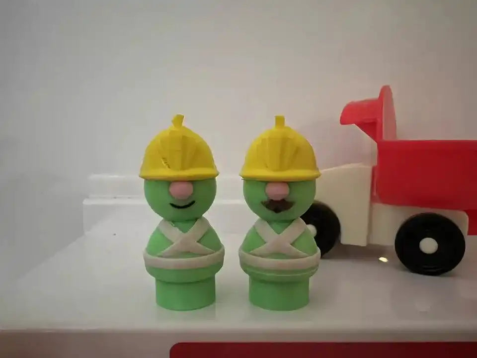 Green Doozer figures with yellow caps and white belts beside a red toy cart