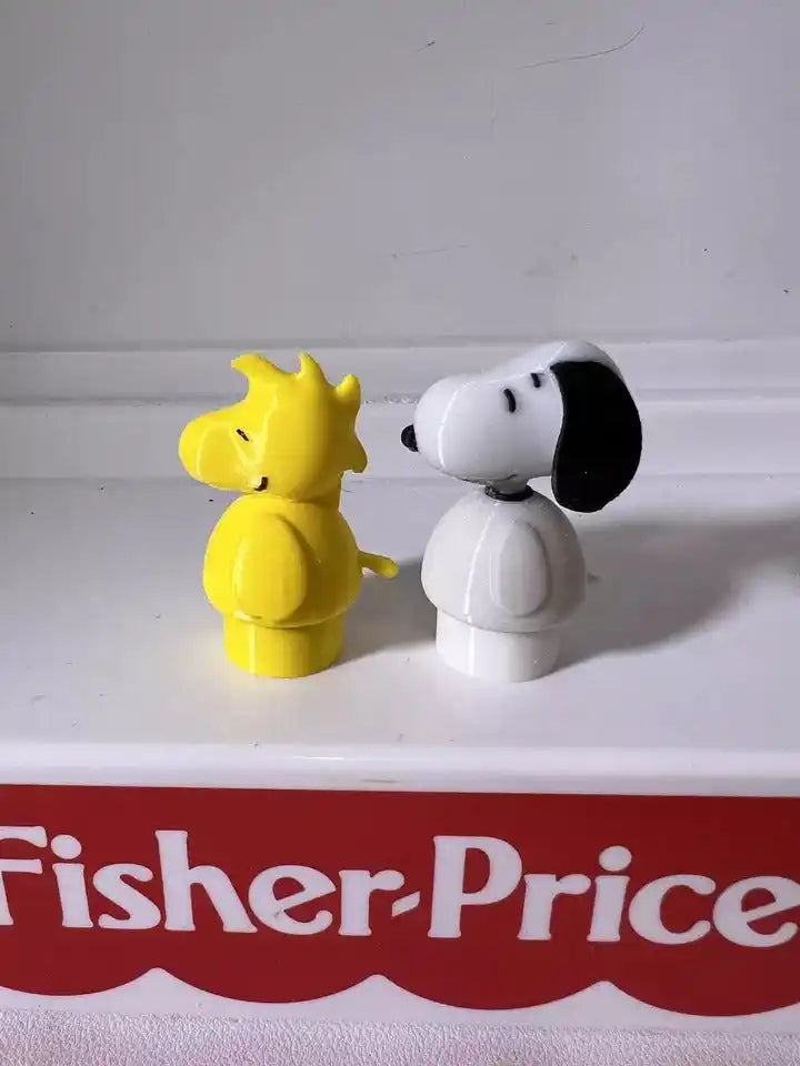 Two small Peanuts figurines: yellow character and Snoopy dog, white with black ear patch