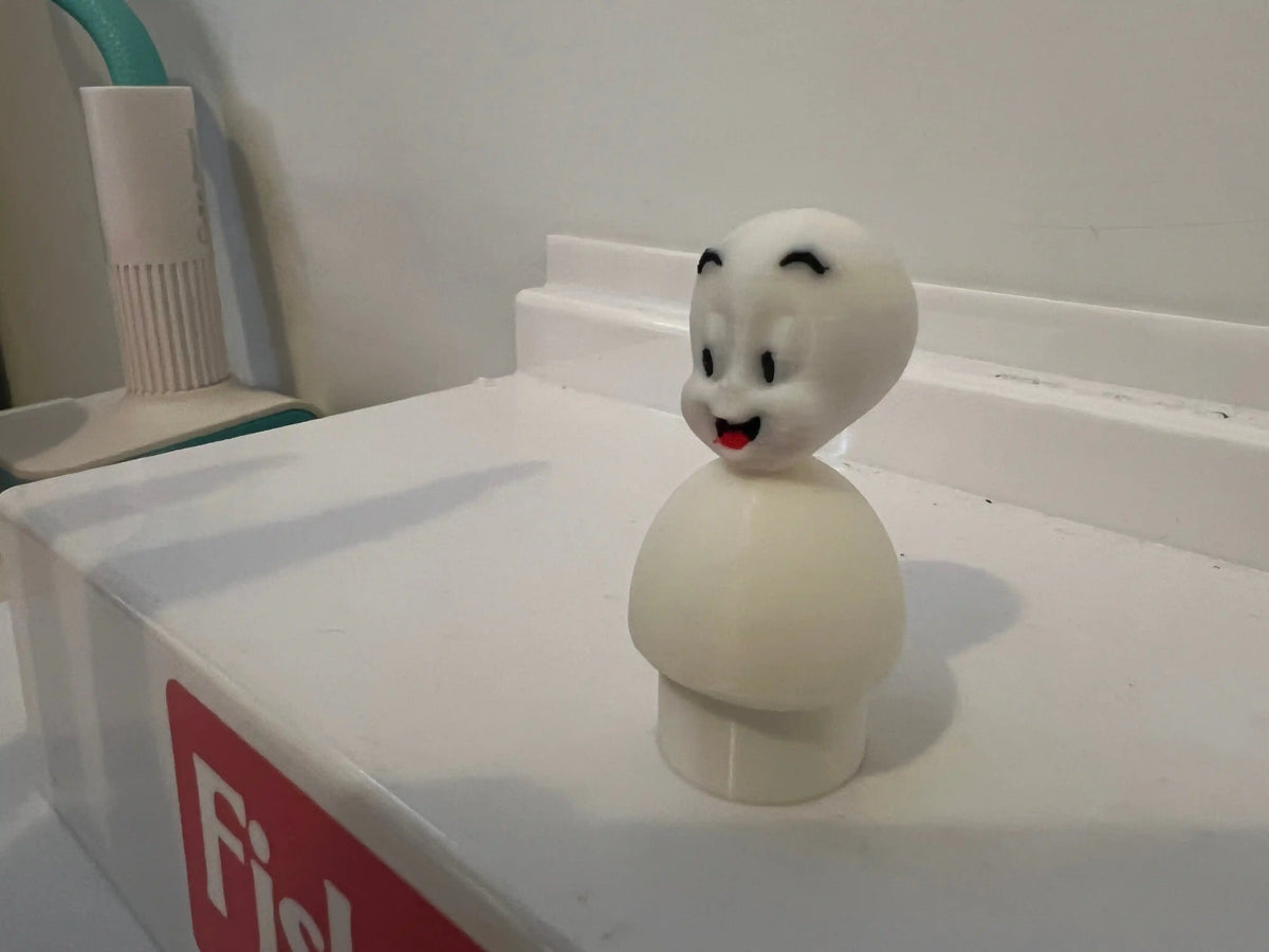 White Casper the Friendly Ghost figurine on a shelf, smiling with black eyes.