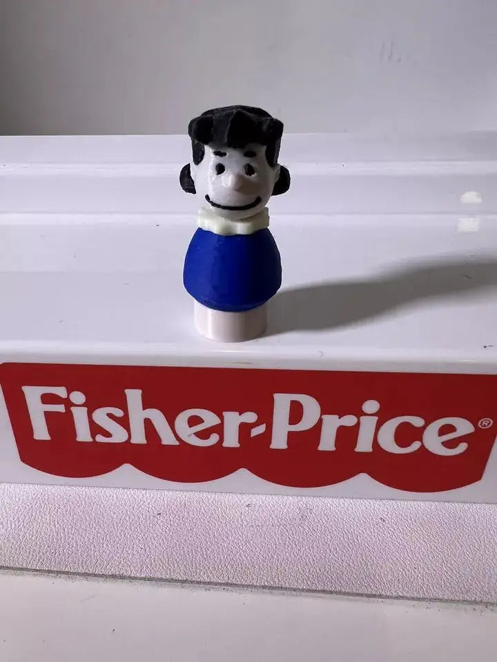 A custom-made 3D printed Little People figure of Lucy Brown from Peanuts, wearing a blue shirt
