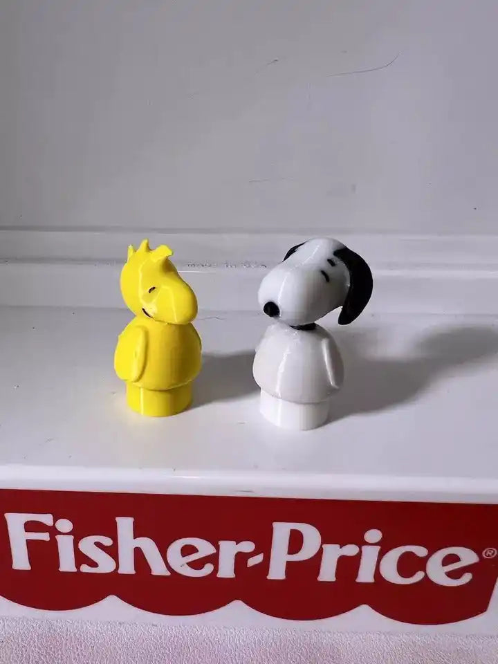 A custom 3D printed Little People-style Snoopy figure in white and black stands next to a yellow Woodstock
