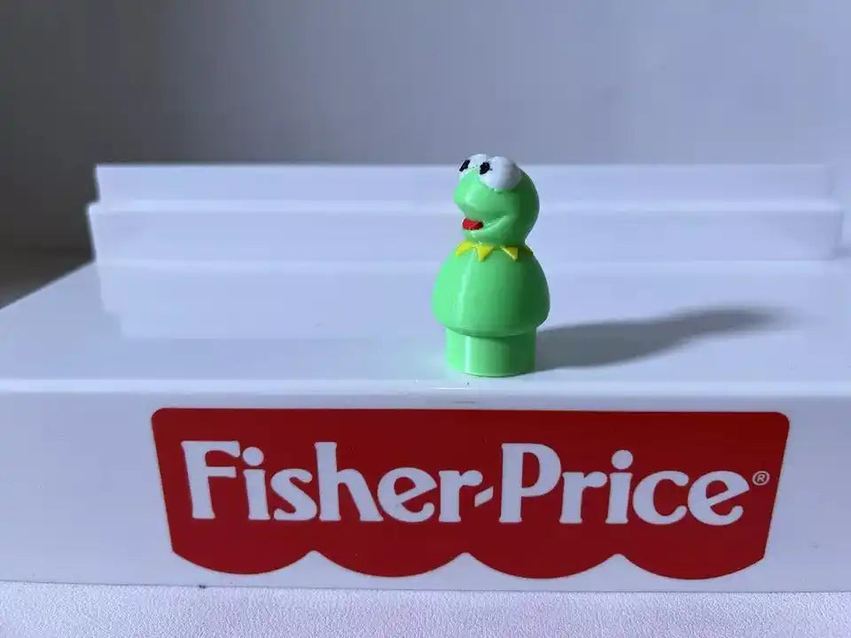 Green frog figurine standing with white eyes and open mouth, side view