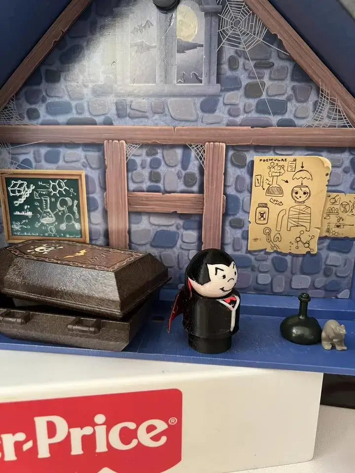 Dracula-style vampire figure in black cloak with red cape, shown near coffin and props.