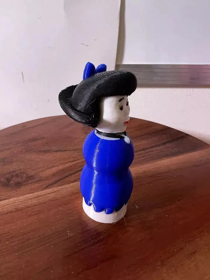 Betty doll figurine in blue dress with black bonnet and blue hair bows