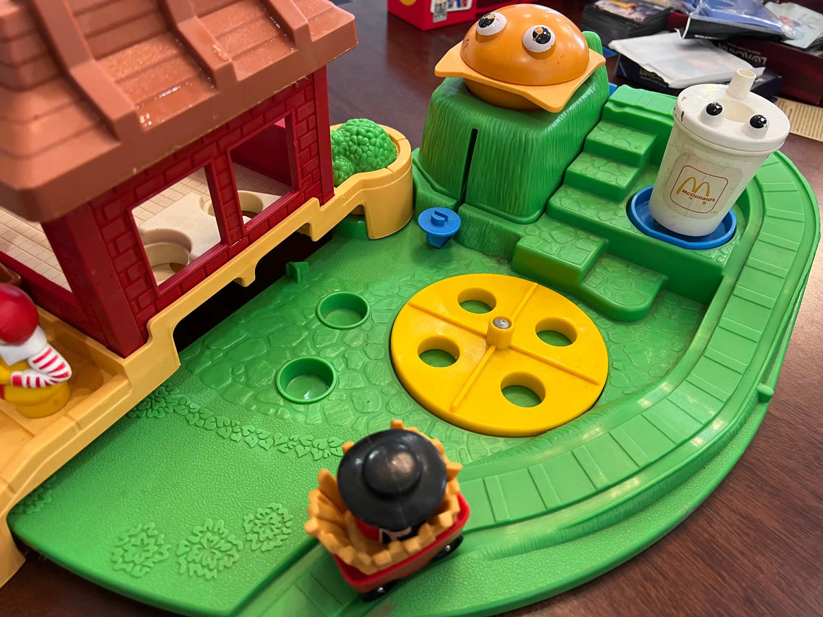 Toy playset green track with yellow spinning wheel and orange/white character figures