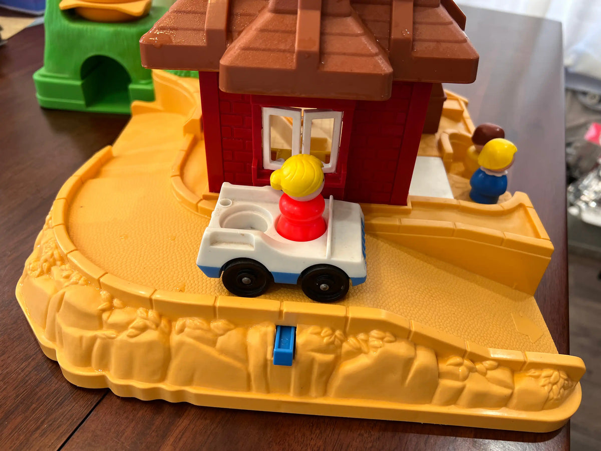 Toy playset with white and red pickup on beige base near red restaurant