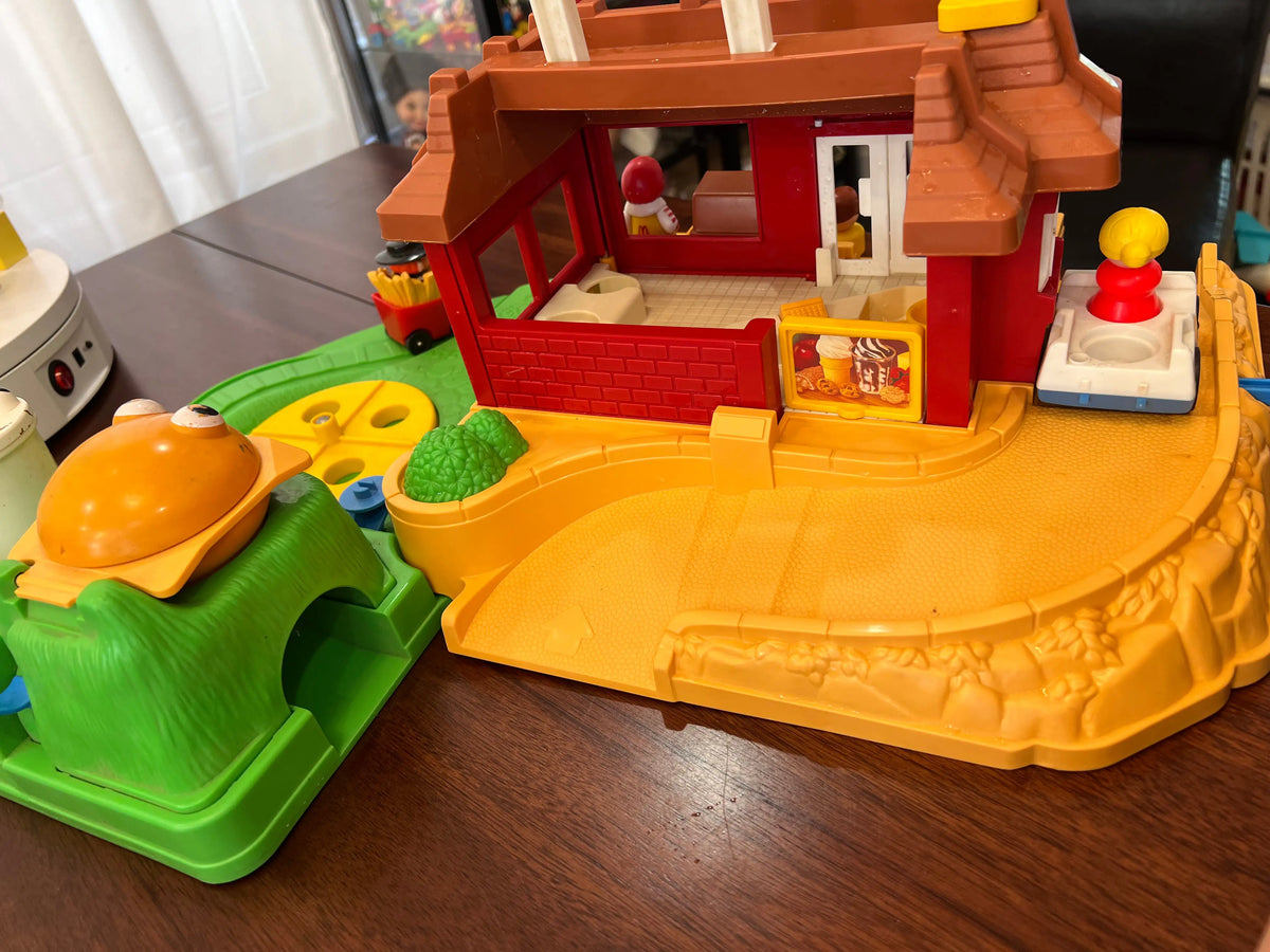 McDonald's playset with red restaurant front, yellow platform, and green accessory track