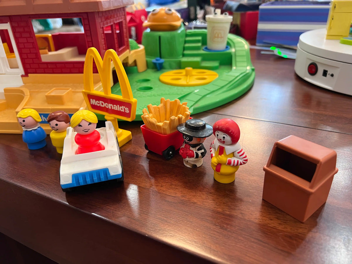 McDonald's toy figures on beige platform near green track and fries accessory