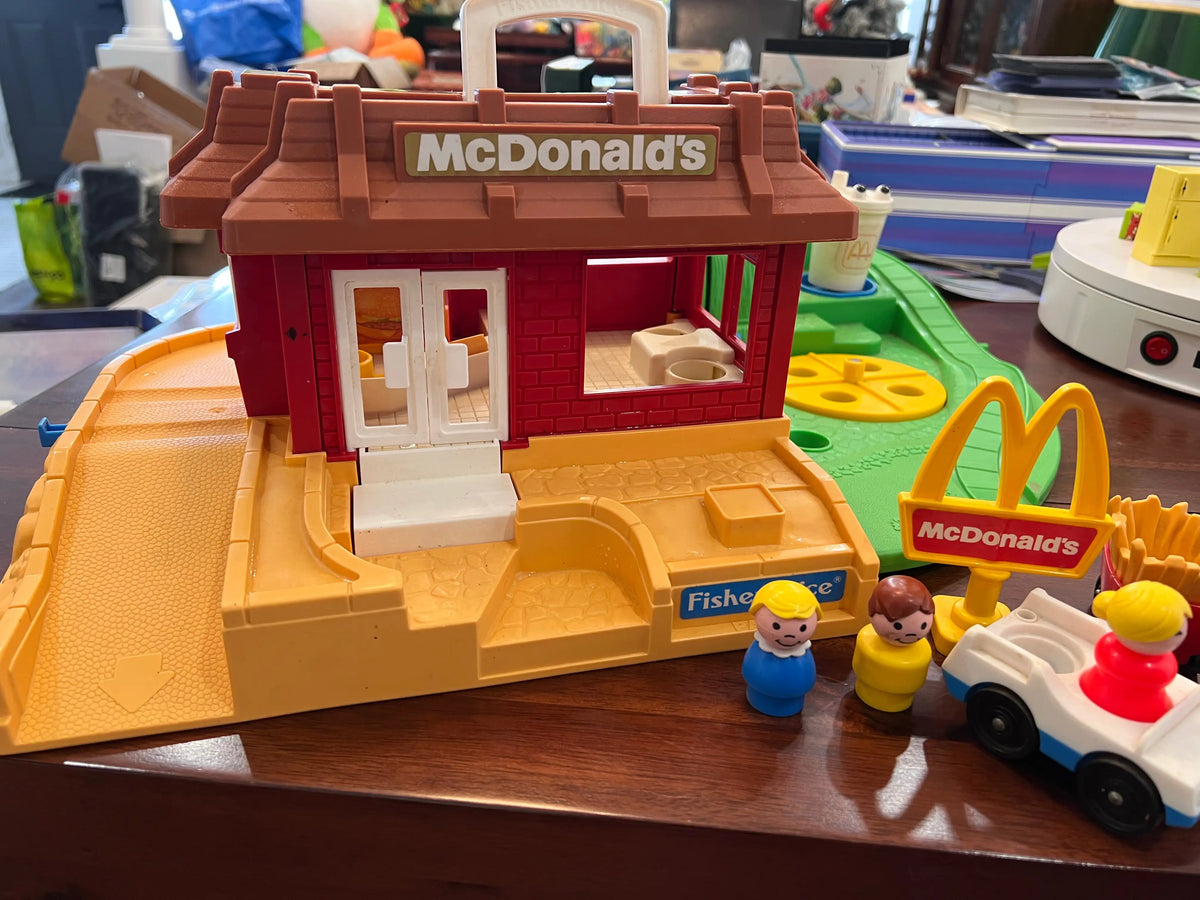 McDonald's restaurant toy playset with red facade, beige platform, and Fisher-Price figures