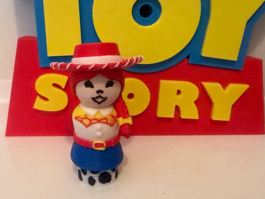 A small Woody character figurine from Toy Story standing in front of a large red and yellow Toy Story sign.