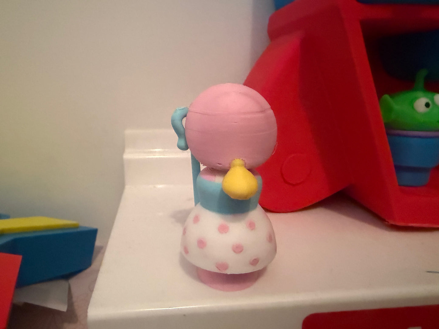 Collectible figure from behind, pink bonnet and blue dress, staff held at side