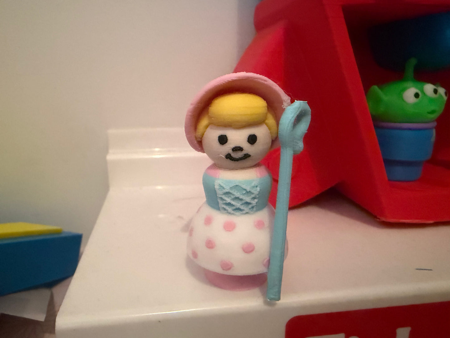 Bo Peep-inspired collectible figure front view, pink bonnet, blue dress and polka-dot skirt