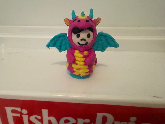 Pink dragon costume plush toy with teal wings and yellow belly, front-facing smile.