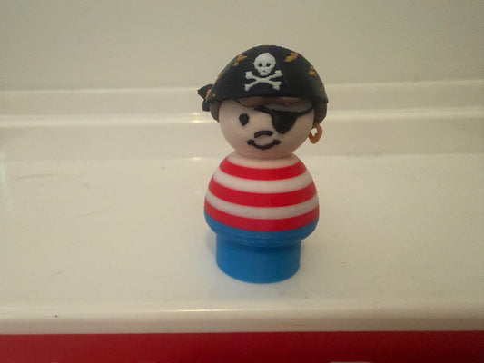 Pirate toy figure front view: black tricorn hat with skull, striped shirt, blue base