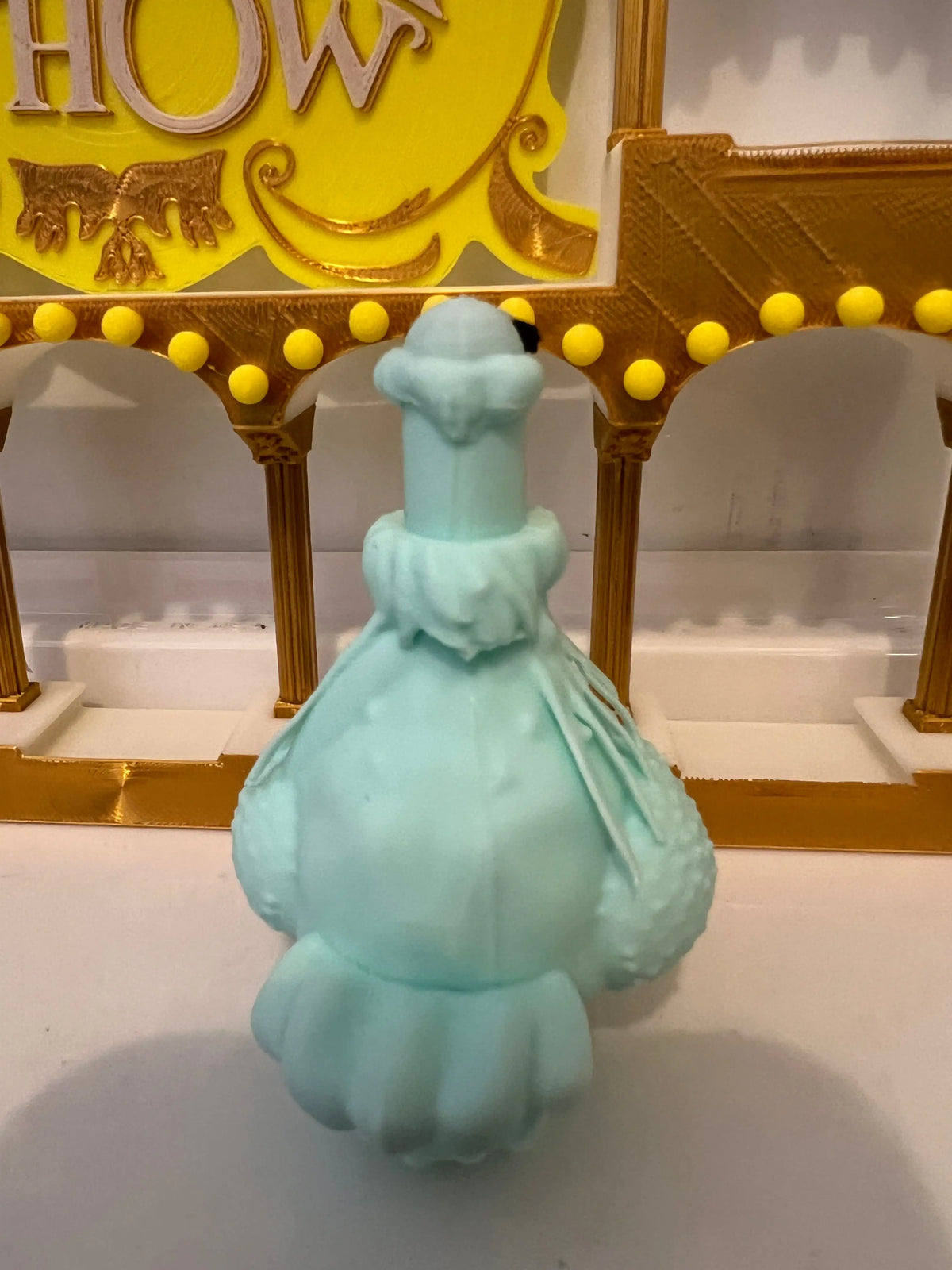 Turquoise plush eagle figurine in a frilly dress, standing pose