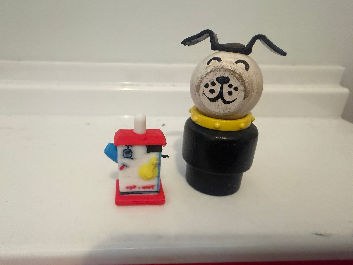 Miniature dog figurine with yellow collar on black base and small red lantern