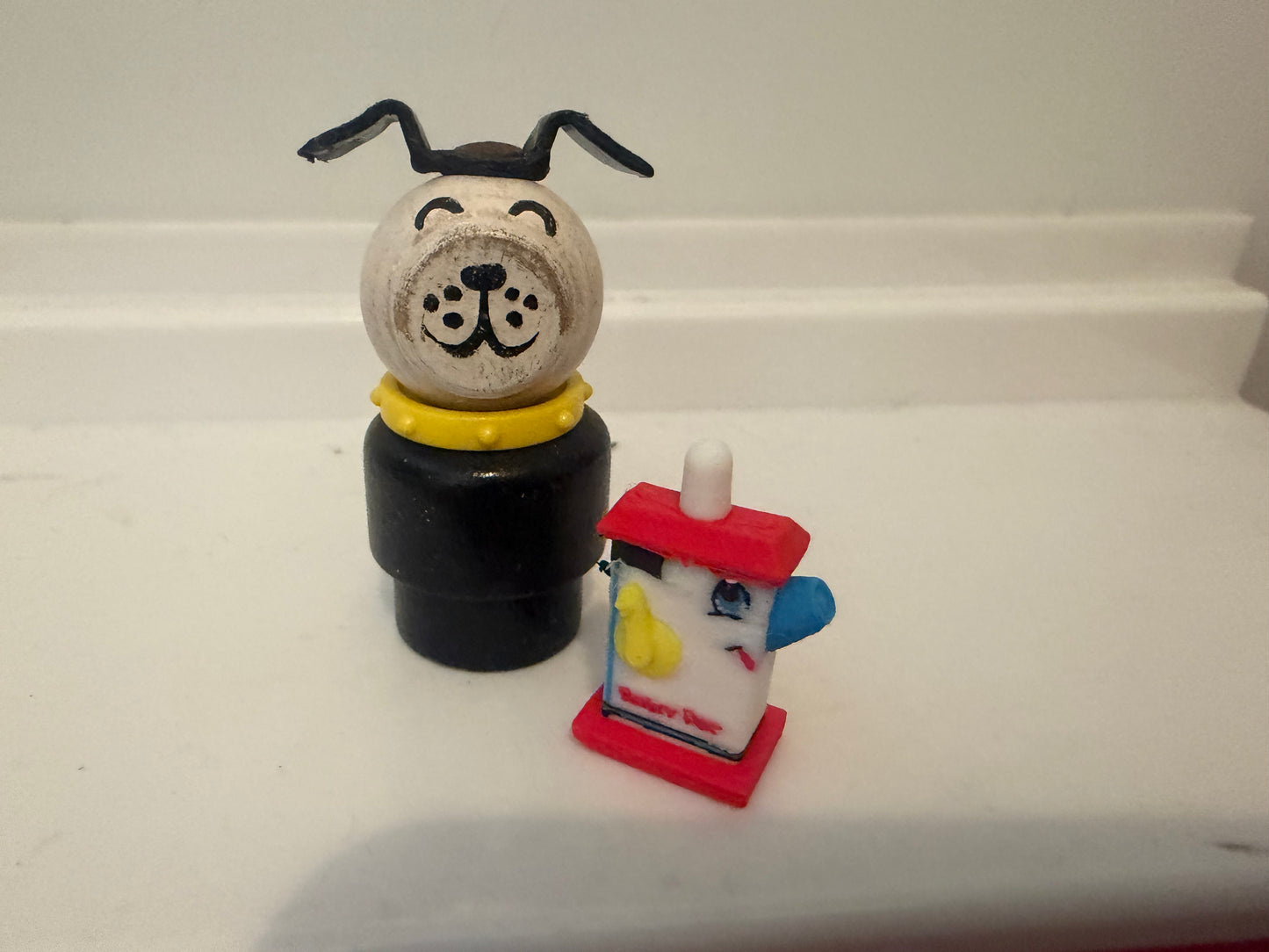 Miniature dog figurine on black base beside small red lantern with blue details