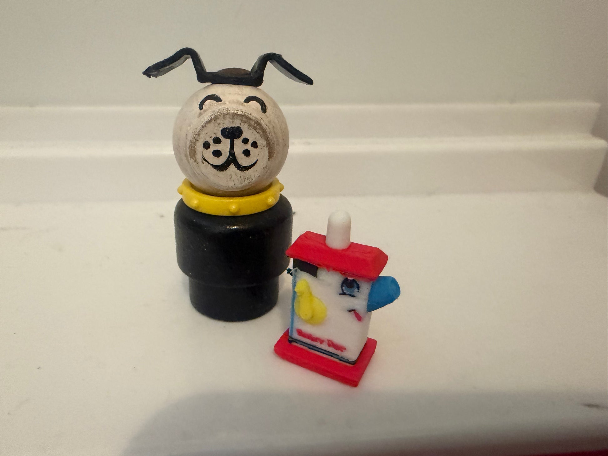 Miniature dog figurine on black base beside small red lantern with blue details