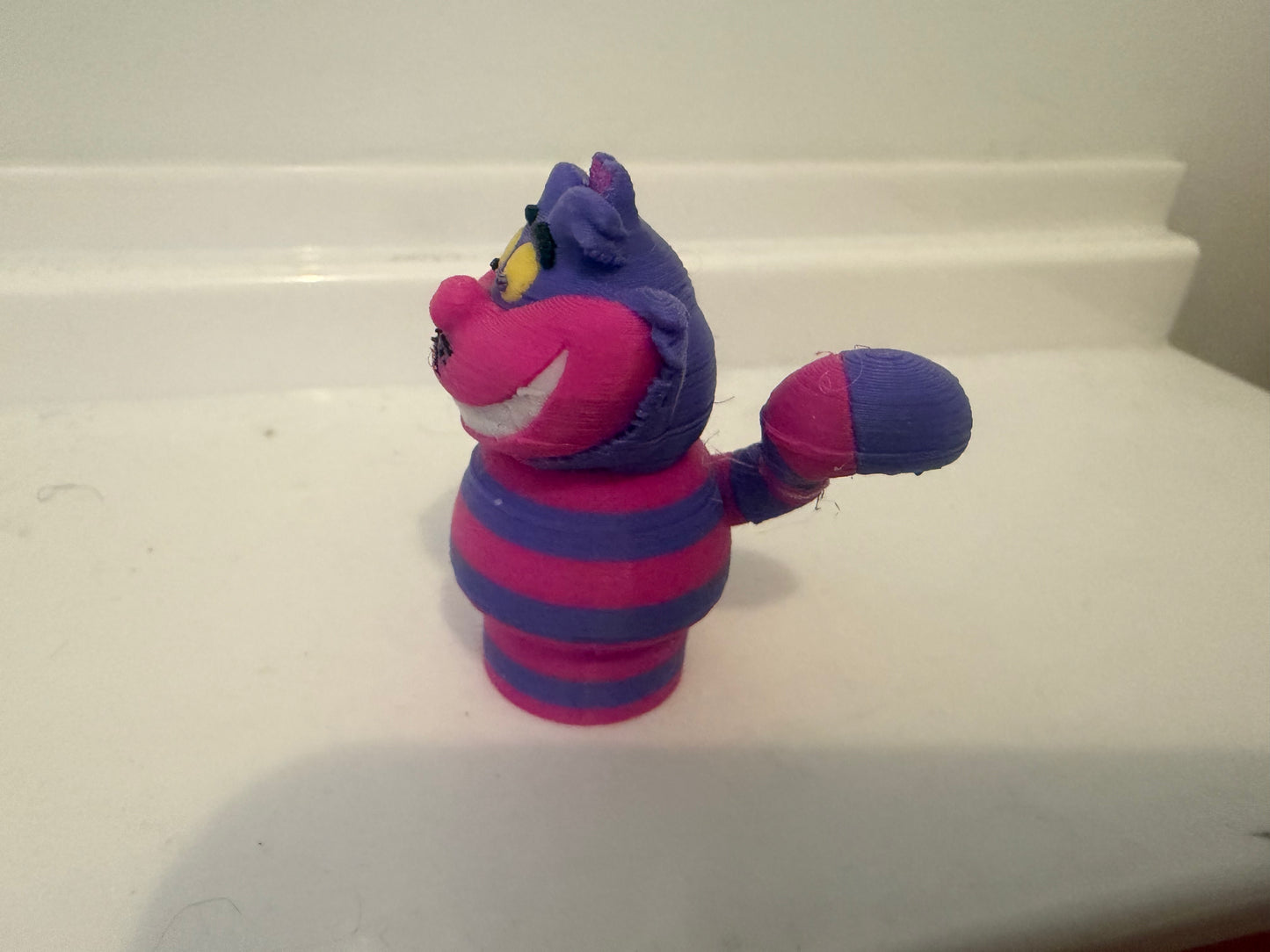 Cheshire Cat plush figure, 3/4 view with raised paw, purple hat and blue/magenta stripes