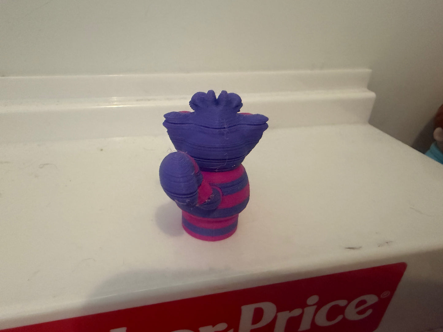Cheshire Cat plush figure, side view, purple top hat and striped blue/magenta body