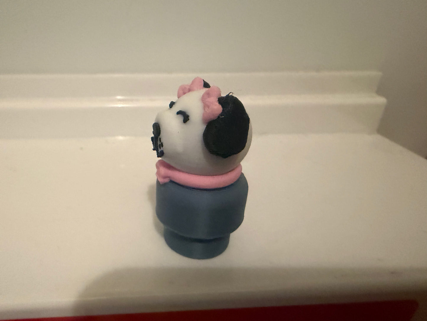 Dog figure toy with white face, pink ears, black patches, navy body, side view
