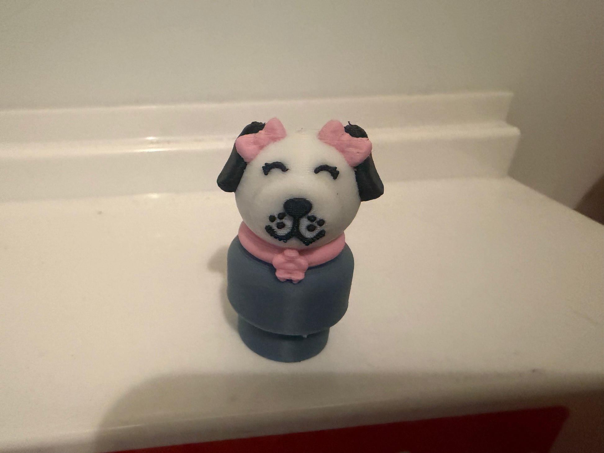 Dog figure toy with white face, pink ears, navy body, smiling facial details