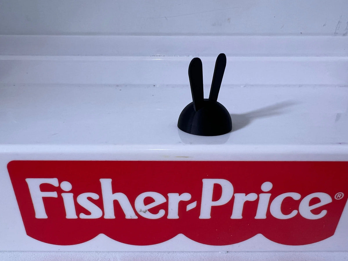 Black rabbit-ear hat with two upright ear shapes on a low rounded base.