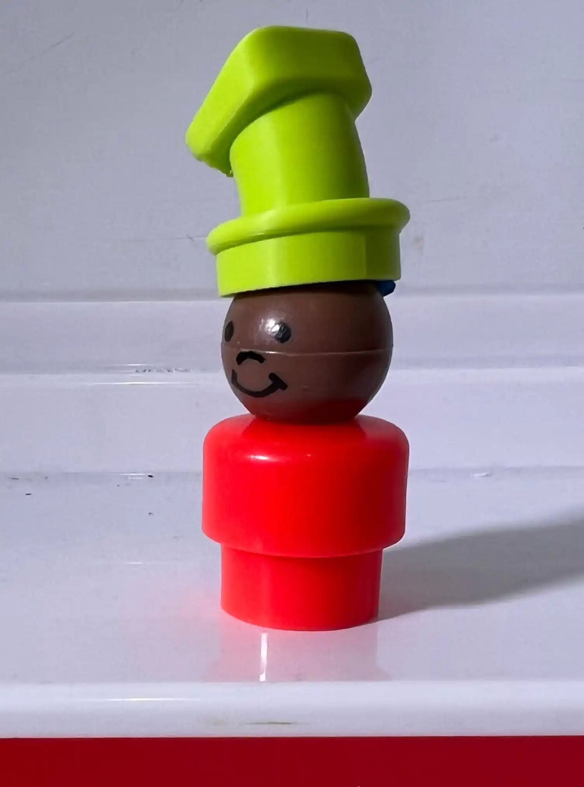 A custom 3D printed lime green Disney-styled Goofy hat accessory atop a brown-headed, red-bodied vintage Fisher-Price Little People figure.