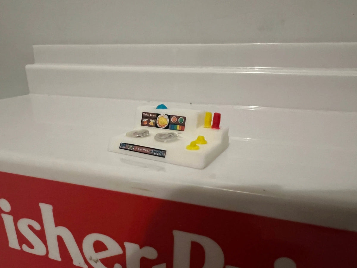 Miniature retro playset sink unit with blue fixtures and small accessory labels