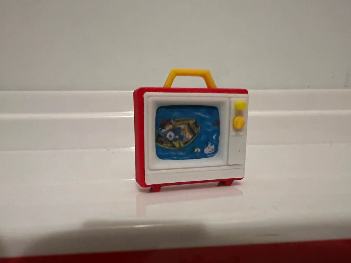 Miniature retro TV with red frame and yellow handle, blue screen with cartoon fish
