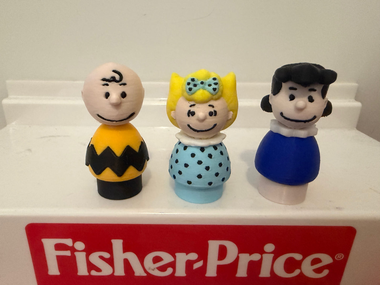 Three Peanuts-style 3D collectible figures with black, yellow, and blue outfits