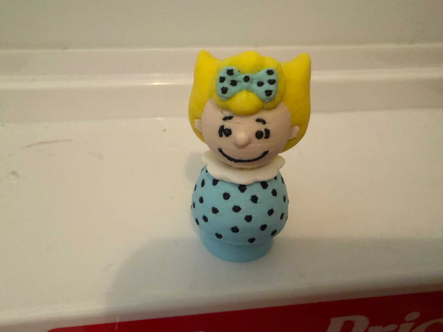 Sally Brown style 3D collectible figure with yellow hair and blue polka-dot dress