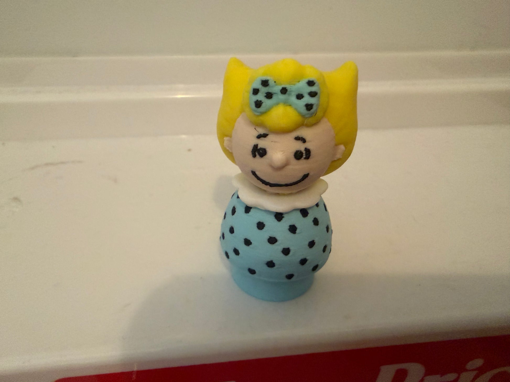 Sally Brown style 3D collectible figure with yellow hair and blue polka-dot dress
