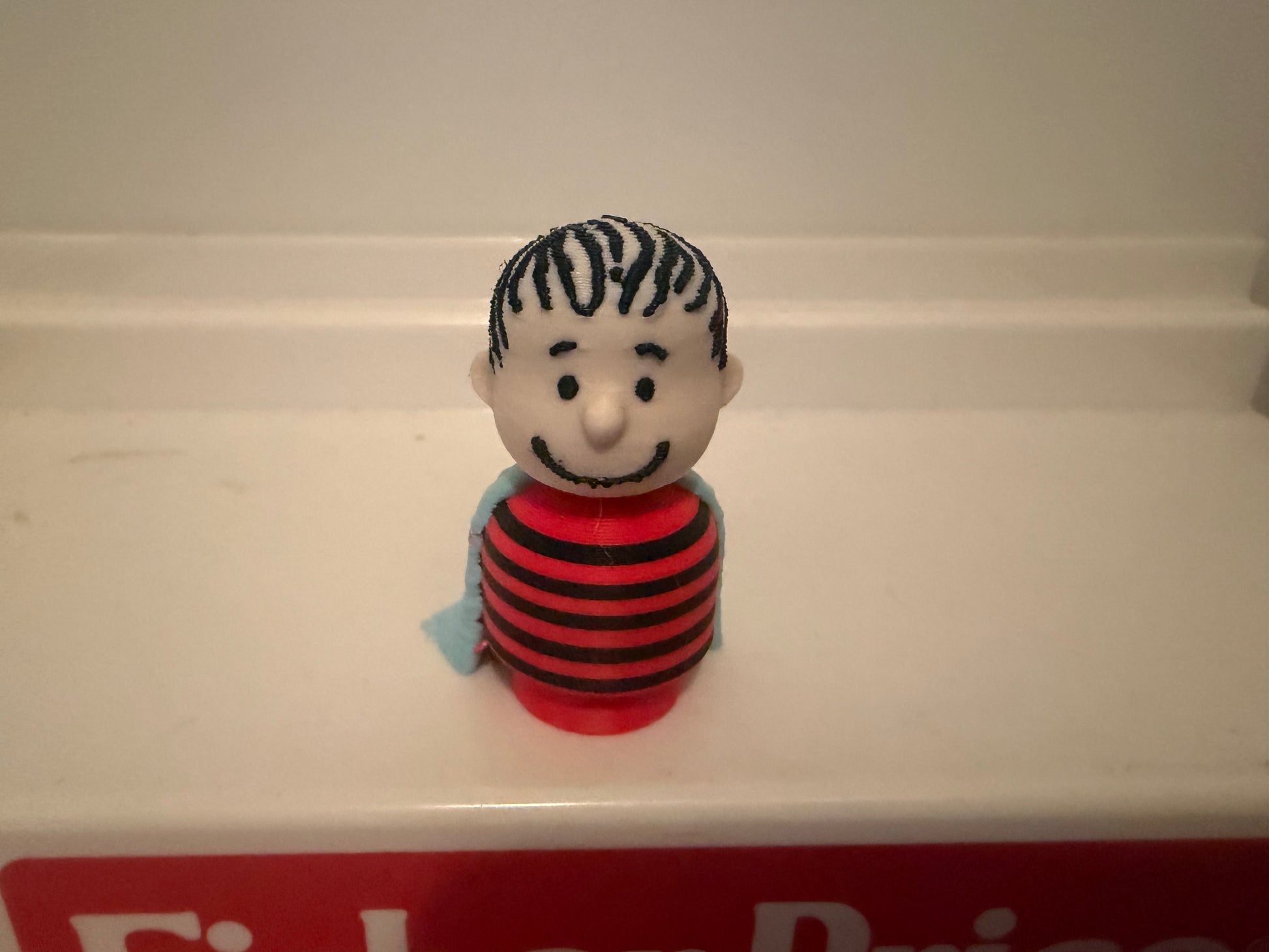 3D Linus collectible figure front view, red-and-black striped shirt and blue blanket